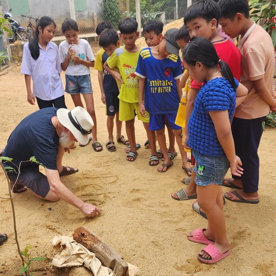 John showing the children how to write Peter